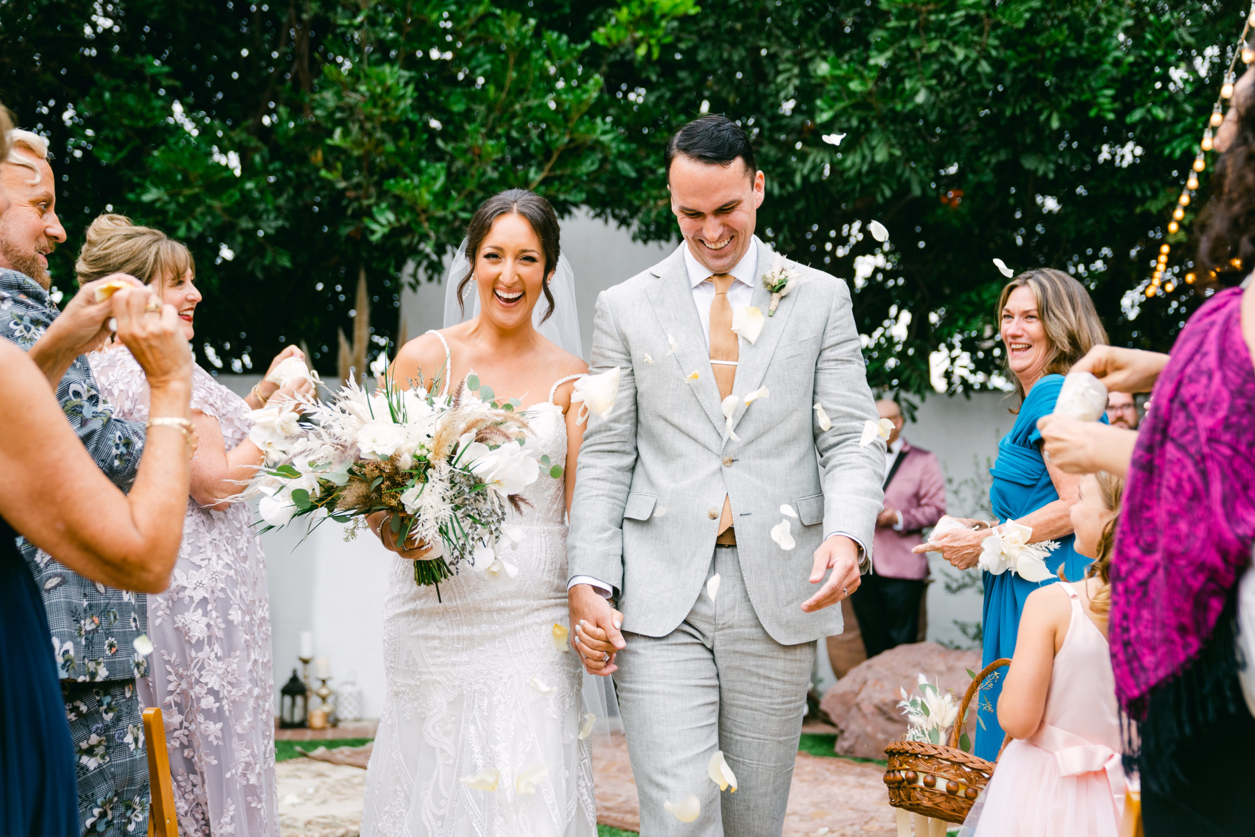 The bride and groom walk down the aisle as confetti is thrown