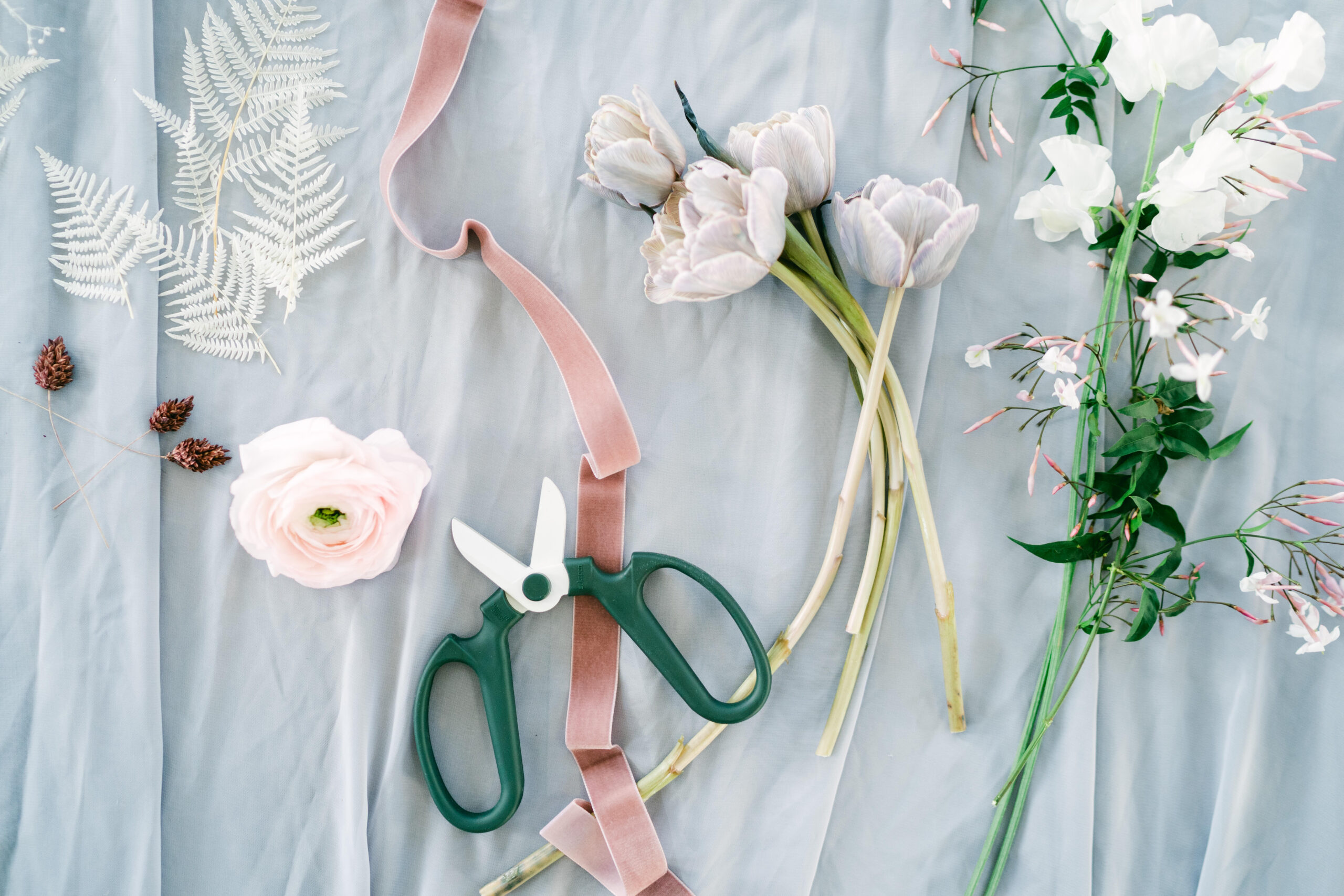 Branding shots for Little HIll Floral Design, one of the best wedding florists in Southern California. Photos taken by Kate Noelle Photography. An overhead shot of several gorgeous floral cuts with pink ribbon and floral scissors.